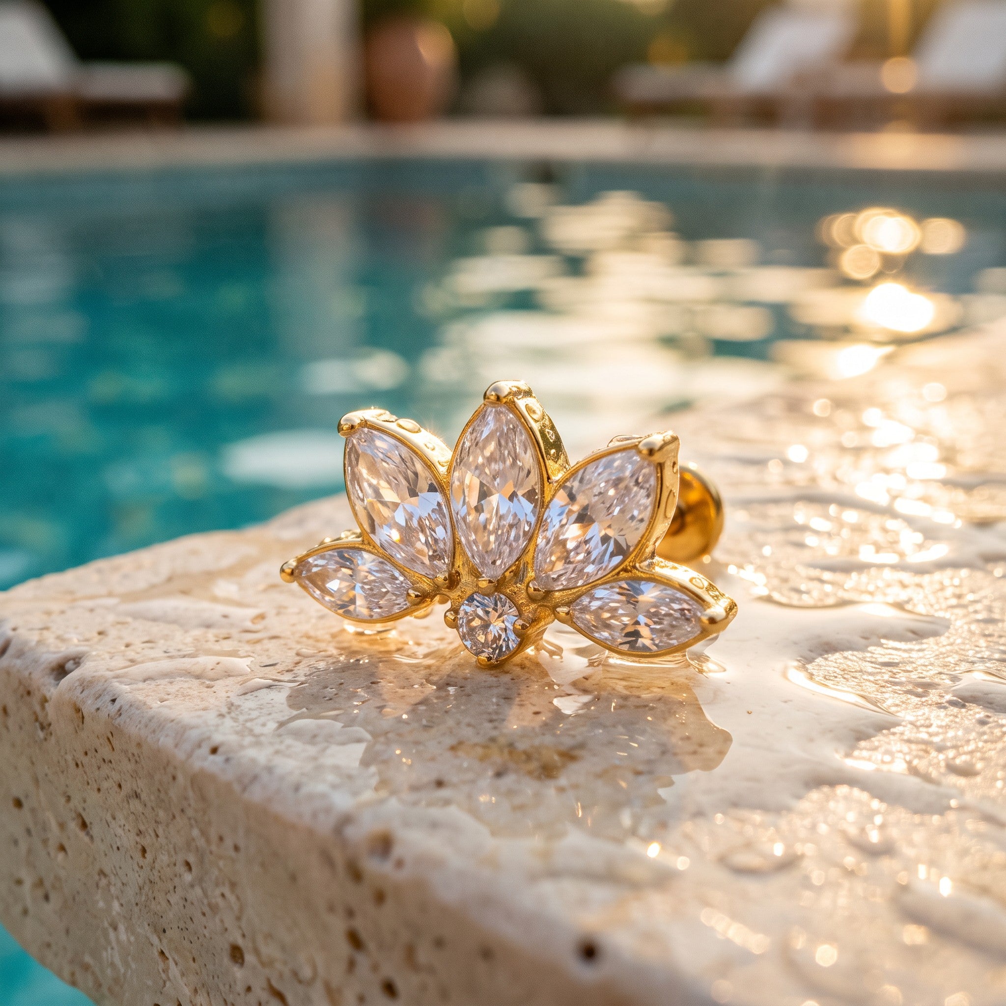 Minaz Piercing Fortuna, wasserfester Lotus Flat-Stecker in Gold am nassen Poolrand mit Wassertropfen