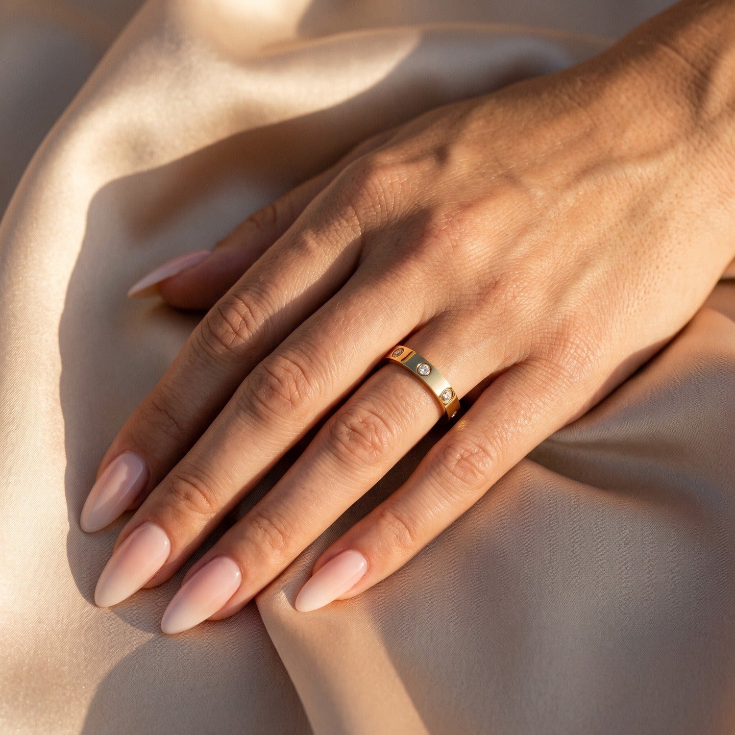 Aisha Ring in Gold am Ringfinger mit Mandel-Nägeln in Pastell-Ombré