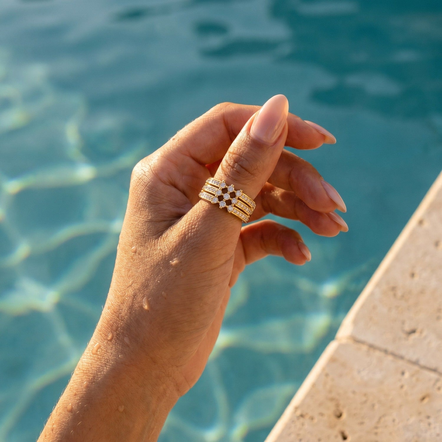 Amina Ring in Gold am Daumen, wasserfest am Pool