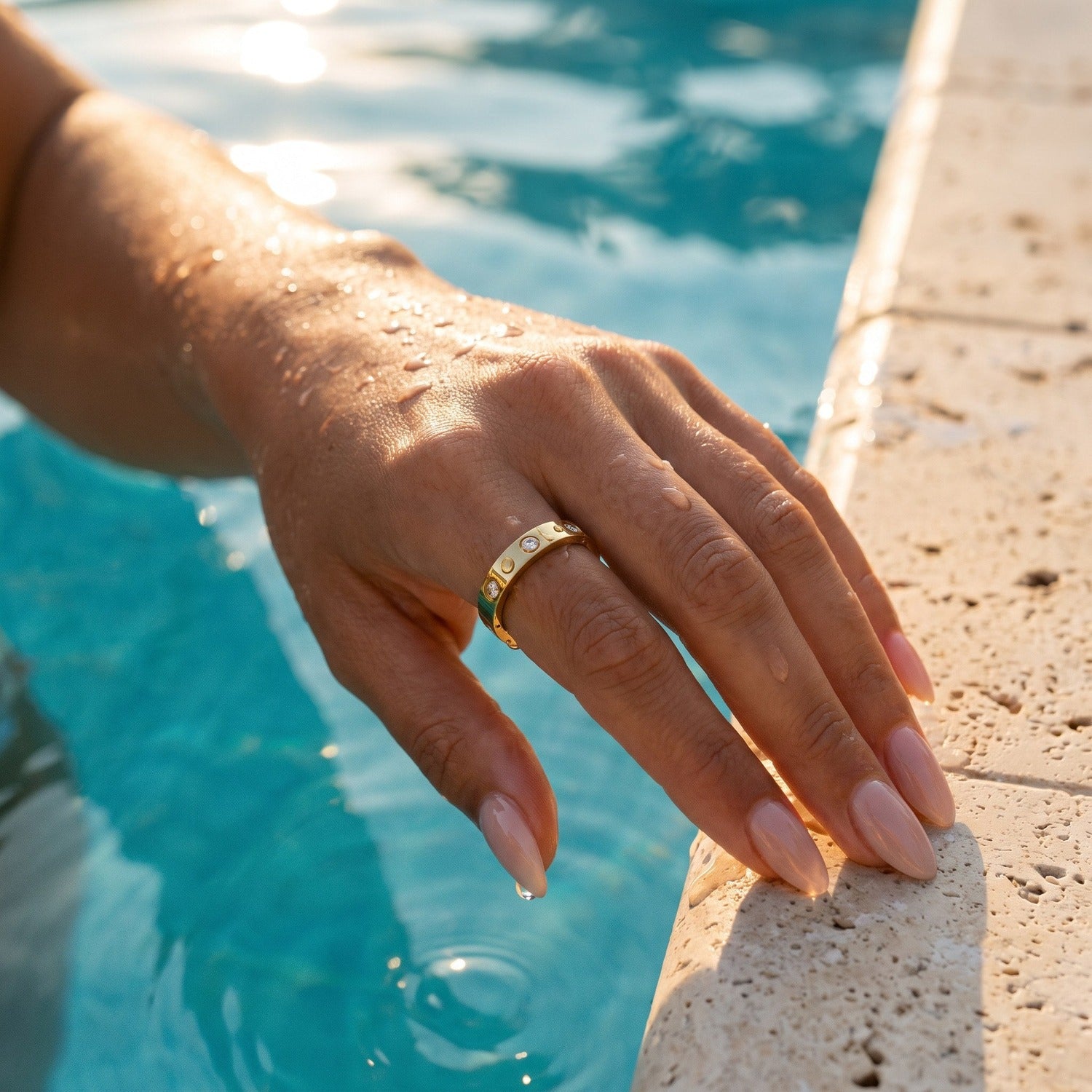 Aisha Ring in Gold, wasserfest am Pool, nasse Hand mit Wassertropfen