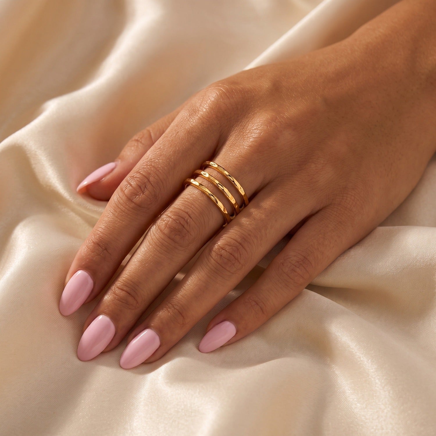 Delia Ring in Gold am Ringfinger getragen auf Satin